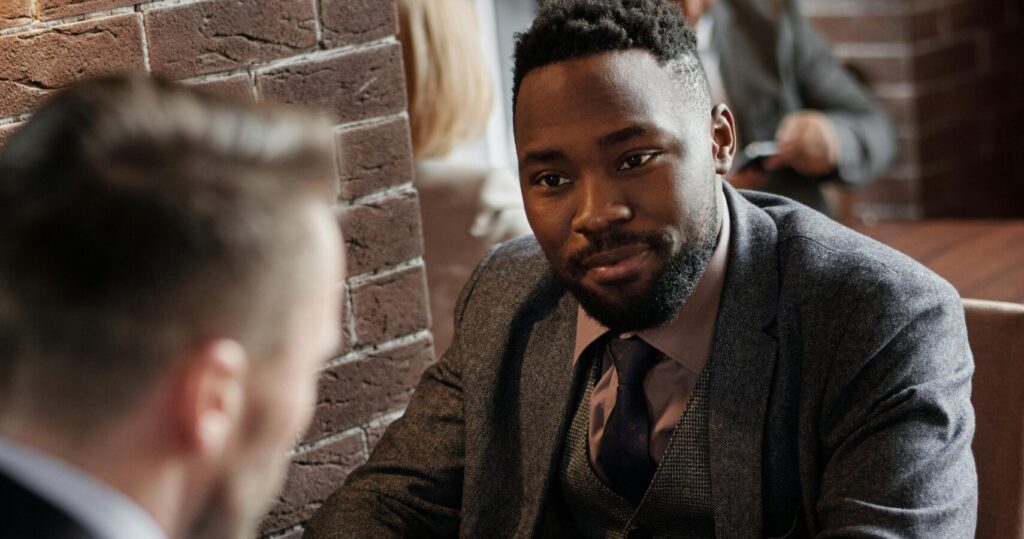 Two businessmen in suits chatting during a coffee break in a stylish café.